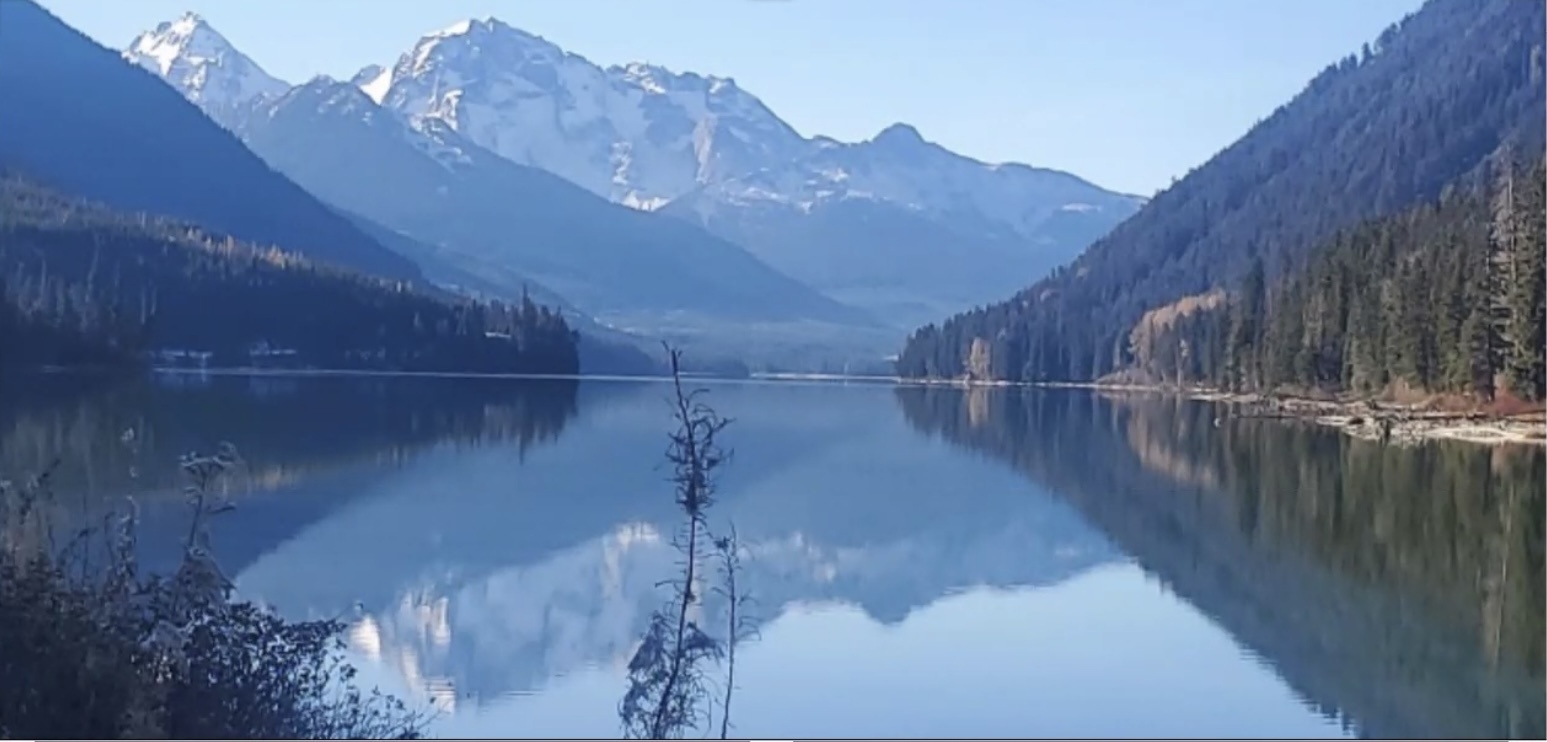 A view of a lake with mountains above and reflected in the lake.