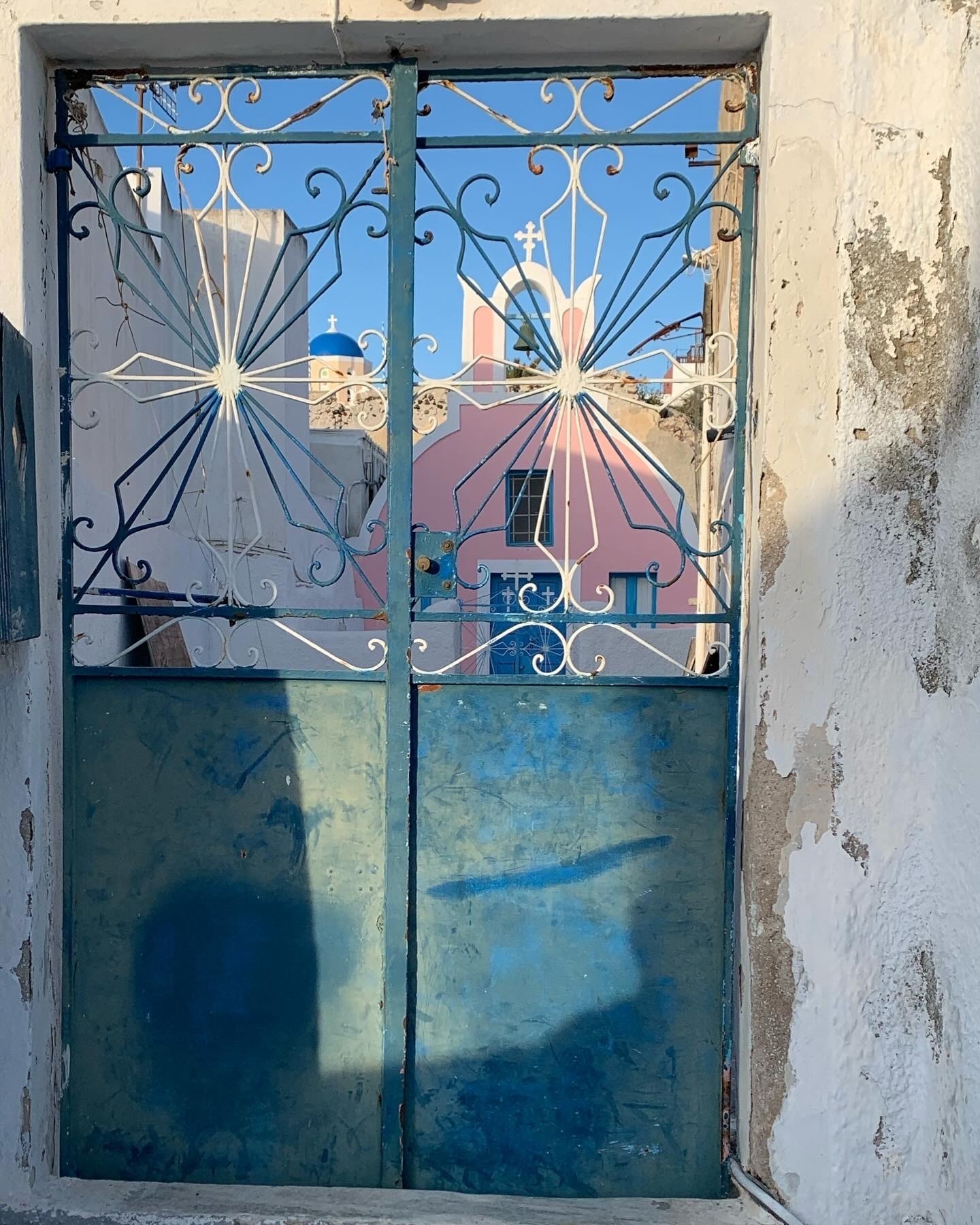 A blue iron door with a pink church in the distance