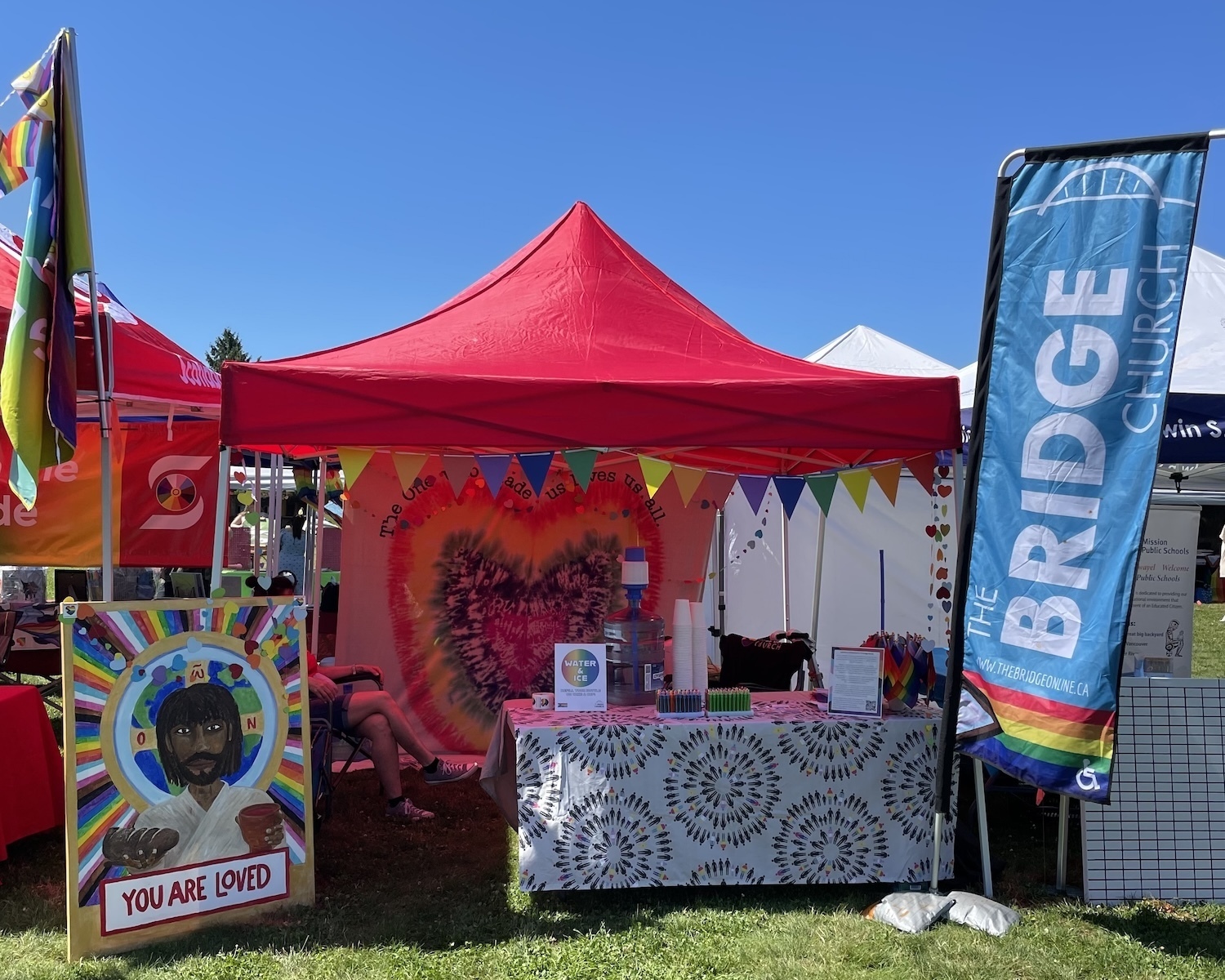 A red tent pride booth set up under the hot sun