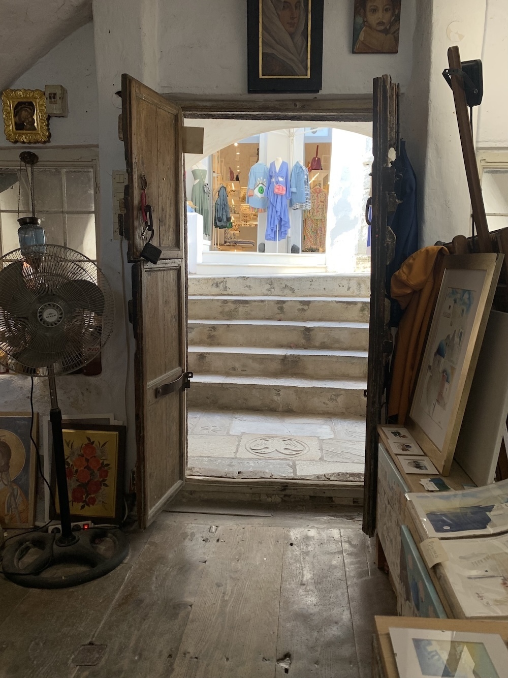 A doorway from one shop looking out into the street and a flight of stairs up to another shop