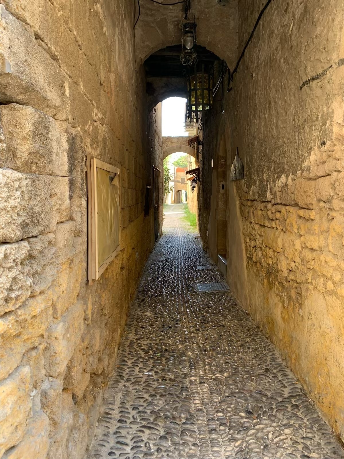 A stone corridor through to an archway with further archways and light beyond